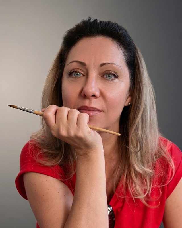 Mihaela David, cu pensula în mână, deasupra caietului de schițe.