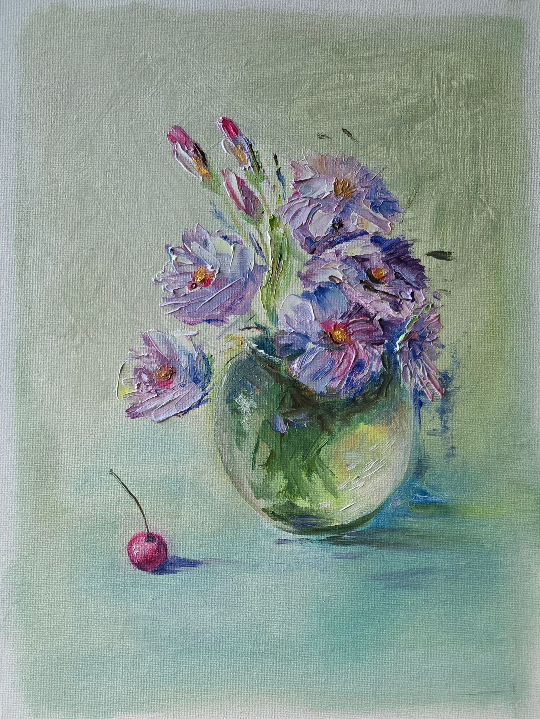 Buchet de flori mov și albe într-un vas rotund de sticlă, cu o cireașă roșie alături, pe fundal verde pal.
